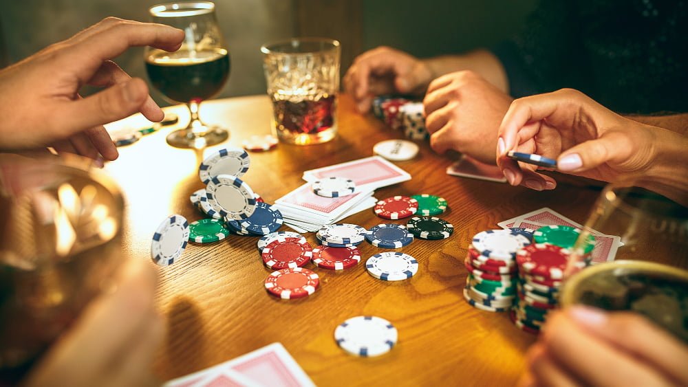 Jogos de cassino: O que jogar? 4 men women playing card game poker evening entertainment excitement concept